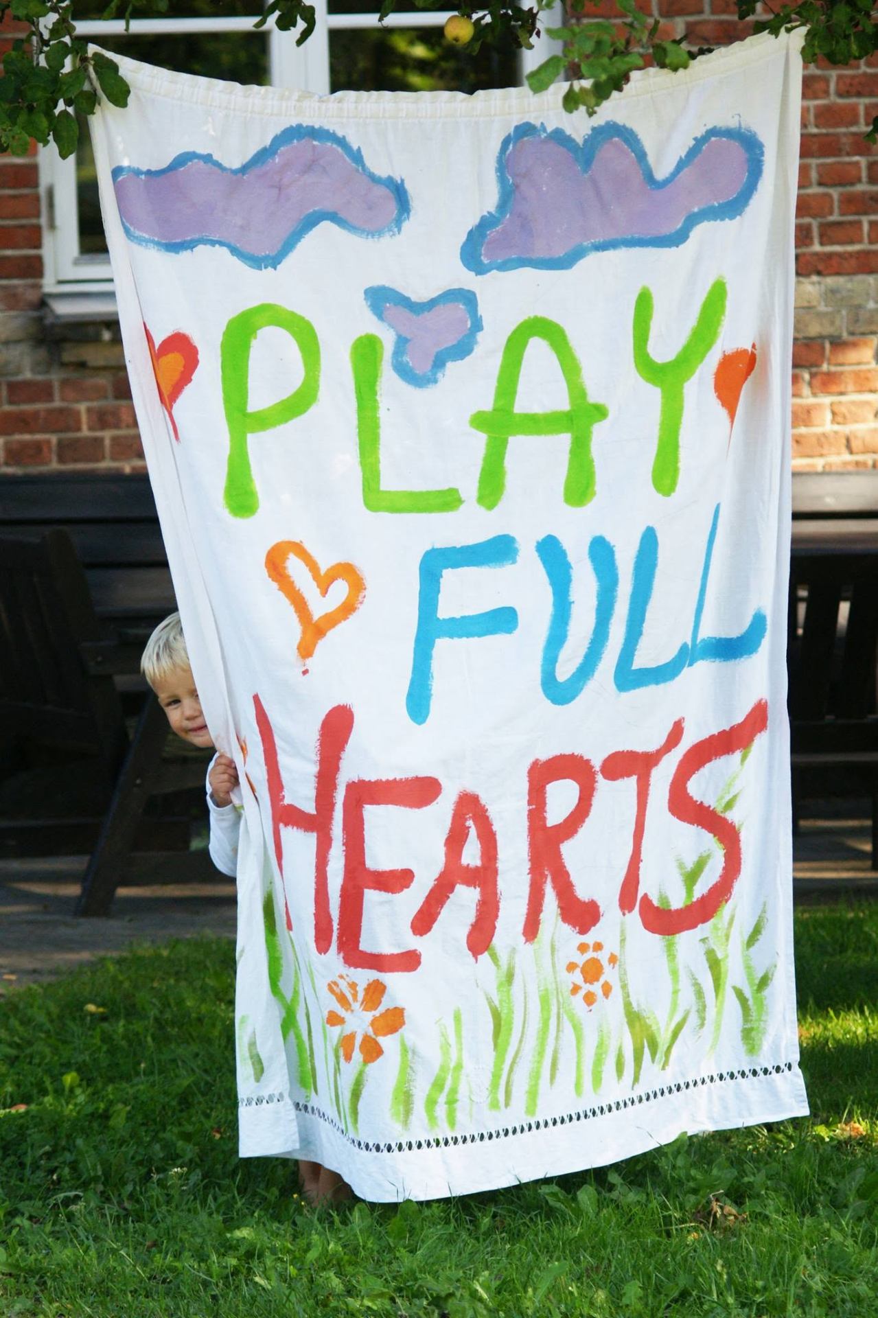 A child holding a hand-painted Play Full Hearts banner